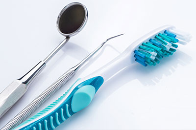 Dental tools, including a toothbrush and dental instruments, are displayed on a white surface.