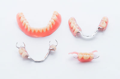 The image displays a collection of dental appliances, including dentures and braces, arranged on a white background.