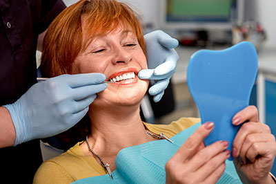 The image shows a person in a dental chair receiving dental care, with a dentist holding up a blue dental impression model.