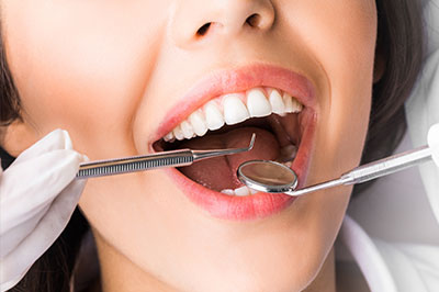 A woman in a dental chair with a dentist performing oral care, focusing on her teeth and gums.