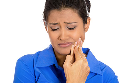 Woman with hand to mouth, displaying a toothpaste tube.