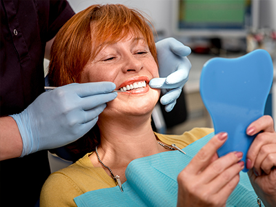 Woman in a dental chair receiving dental care with a smile on her face.