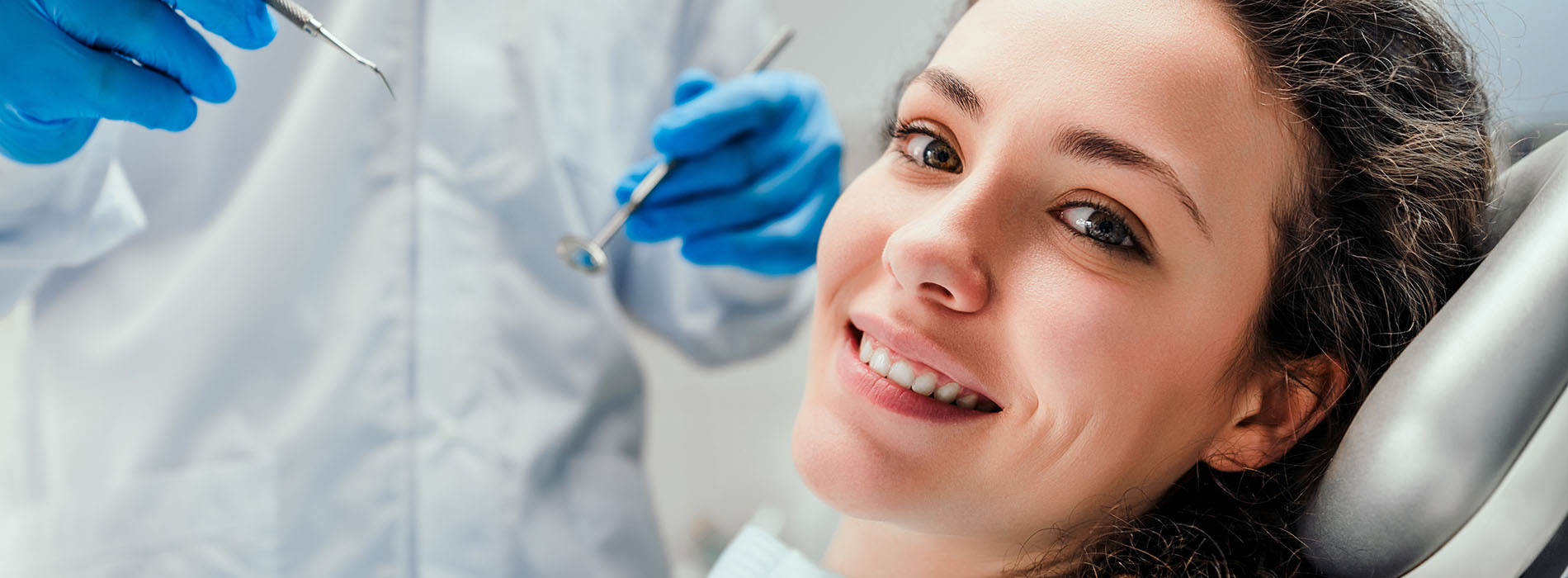 Woman receiving dental care with a smiling expression, surrounded by dental professionals in a sterile environment.