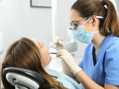 A dental hygienist is performing a teeth cleaning procedure on a patient in a dental office.