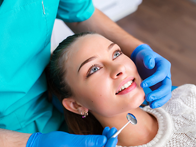 The image shows a dental professional performing a procedure on a patient in a dental office setting.